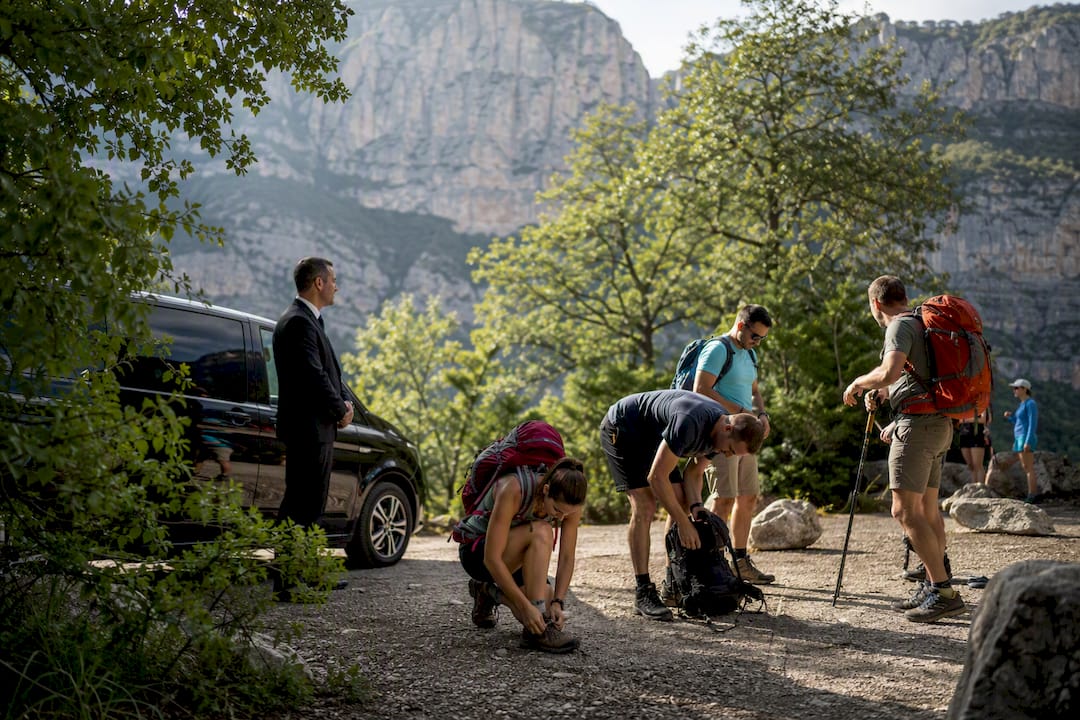Chauffeur with luxury Mercedes sedan alongside hikers at Sentier Blanc-Martel trail start