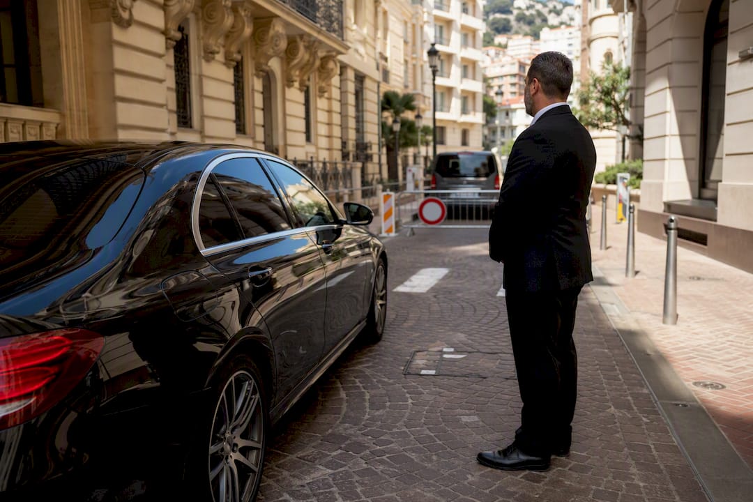 Business sedan and chauffeur near Monaco road closure signs