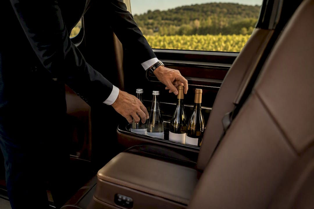 Chauffeur arranging bottled water and wine inside luxury Mercedes-Benz car