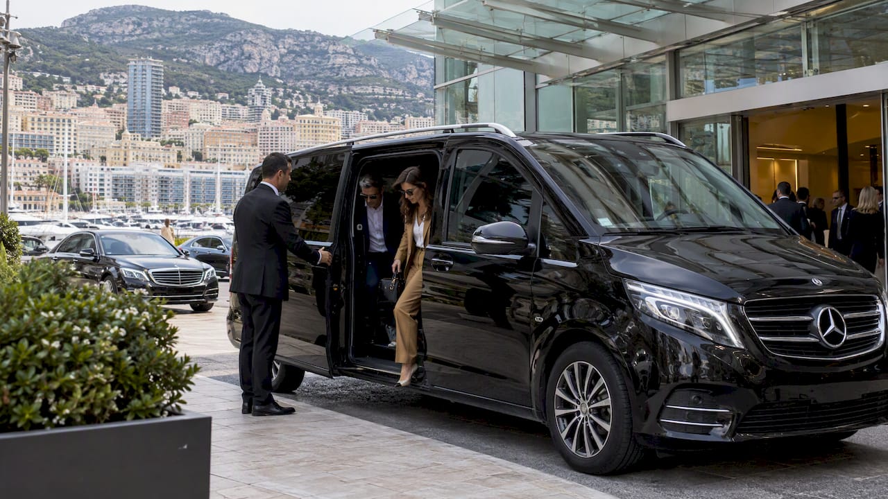 Mercedes-Benz van delivering delegates for Monaco event transportation at a convention venue.