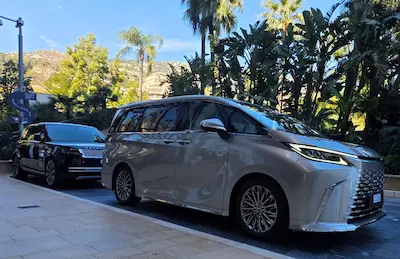 Un van de luxe TranspOnyx stationné sous les palmiers, symbolisant un transport exclusif sur la Côte d'Azur pour une clientèle VIP.