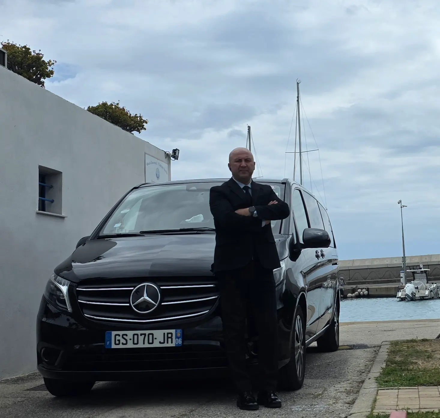Private chauffeur in formal suit standing by the TranspOnyx Van at Port Saint Laurent du Var, ready for a transfer to Nice Côte d'Azur Airport